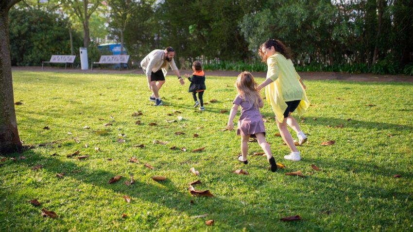 A joyful family playing together in a lush green park setting, enjoying a bright day.
